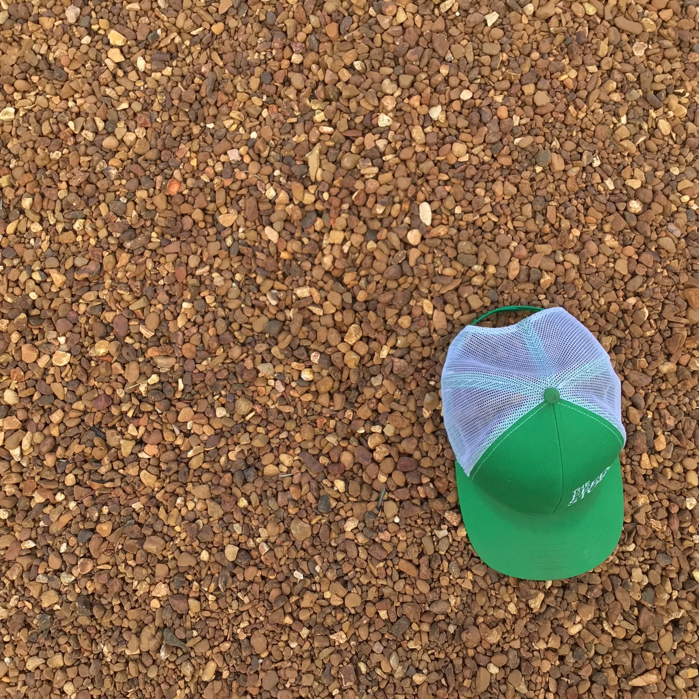 A green and white cap placed on top of pea gravel.