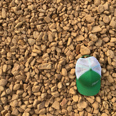 A green and white cap placed on a bed of orange river rock gravel.